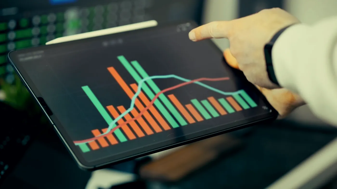 A hand on a tablet that shows bar and line charts