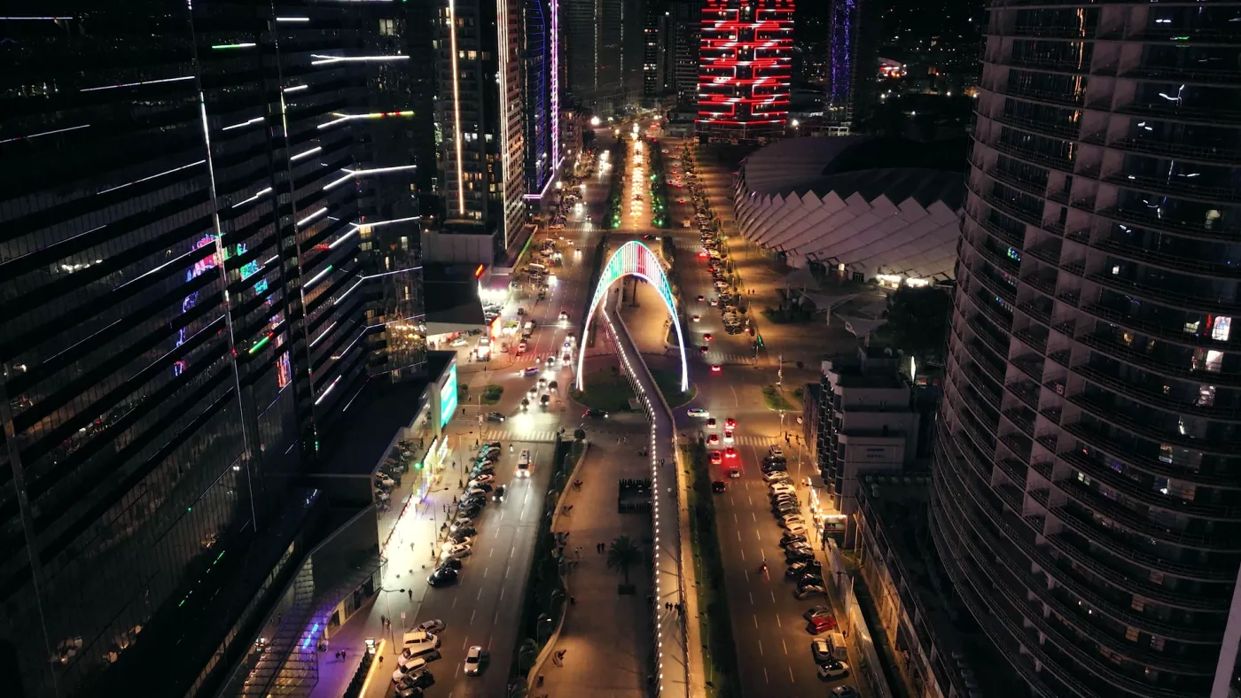 A lit boulevard between towers at night, seen from above