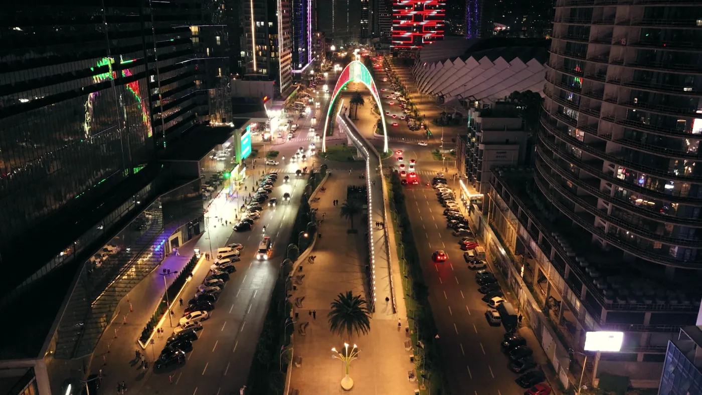 The same boulevard further along, with traffic and a lit footbridge